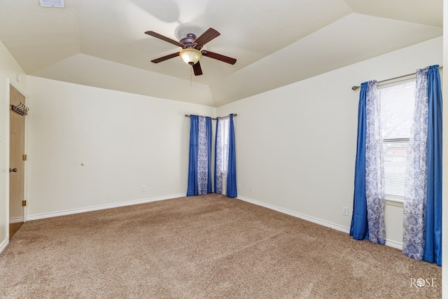 carpeted empty room with a tray ceiling, lofted ceiling, visible vents, a ceiling fan, and baseboards