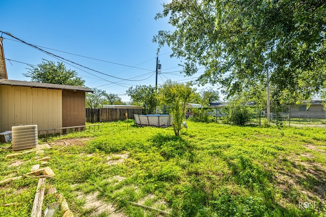 view of yard with a fenced in pool and central air condition unit