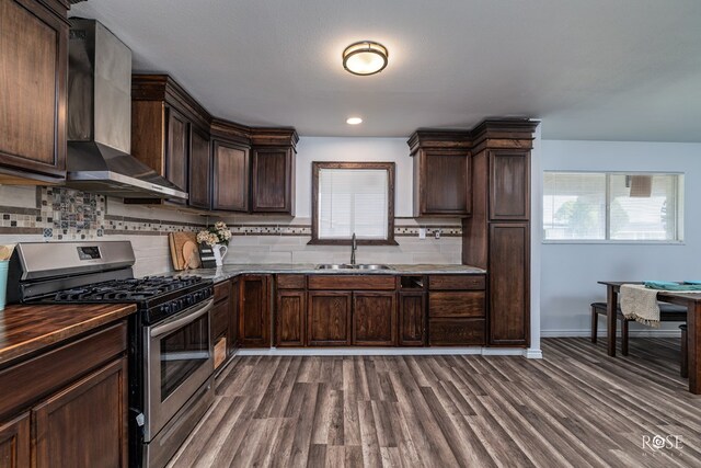 kitchen with stainless steel range with gas cooktop, tasteful backsplash, sink, dark brown cabinets, and wall chimney range hood