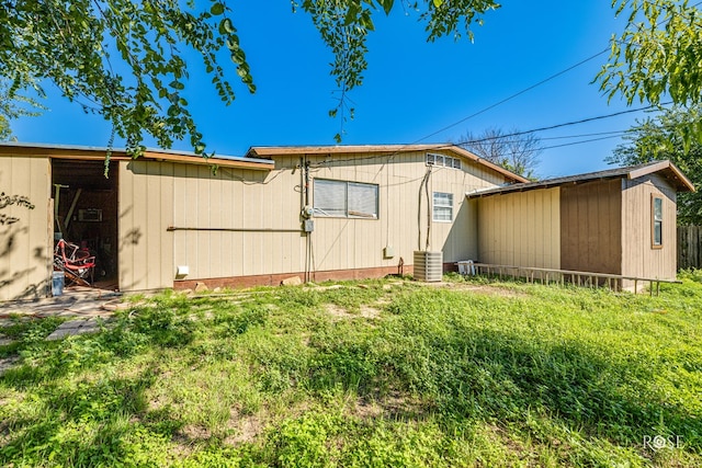 back of property with cooling unit and a lawn