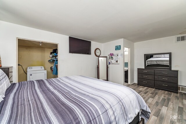 bedroom featuring connected bathroom, washer / clothes dryer, hardwood / wood-style floors, and a closet