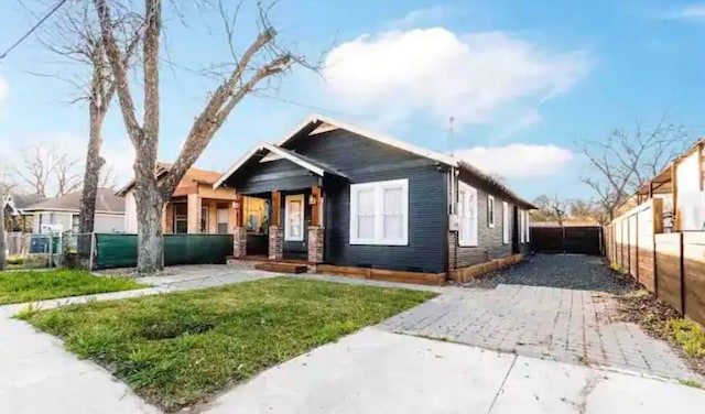 bungalow-style home with gravel driveway, a front lawn, and fence