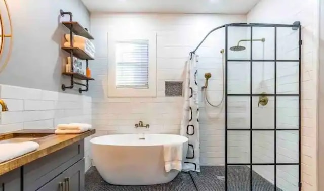 full bathroom with a tile shower, tile walls, vanity, and a freestanding tub