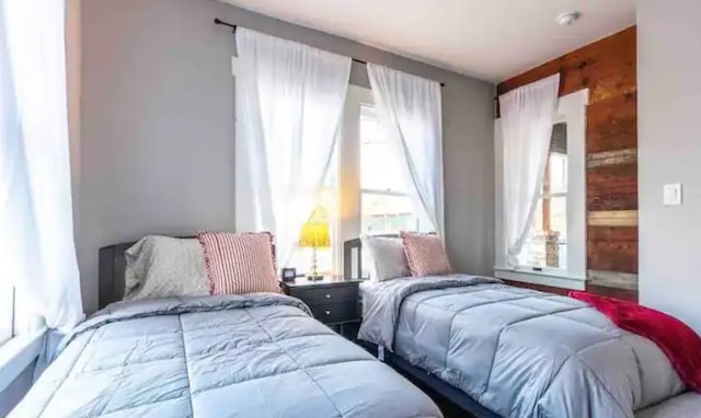 bedroom featuring multiple windows and wood walls