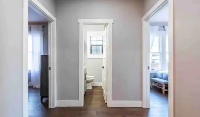 corridor with baseboards and dark wood-style flooring