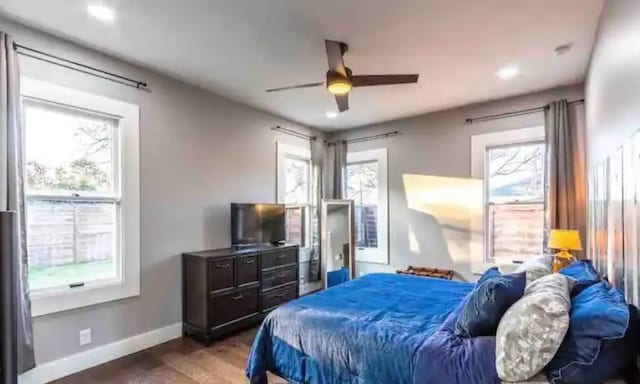 bedroom with multiple windows, ceiling fan, baseboards, and wood finished floors