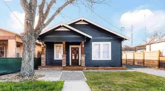 bungalow-style house with a front yard and fence