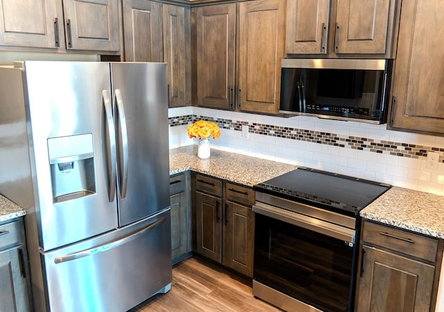 1901 Chesney Ln, San Angelo, TX 76904 - kitchen featuring appliances with stainless steel finishes, decorative backsplash, dark brown cabinetry, and light wood-style floors
