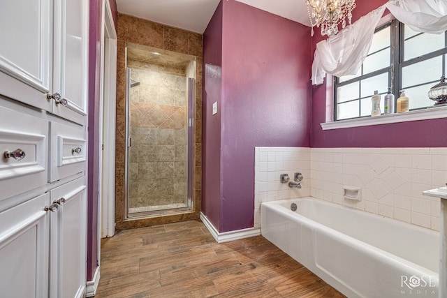 3405 Shadyhill Dr, San Angelo, TX 76904 - bathroom featuring a bath, wood finished floors, a stall shower, baseboards, and a chandelier