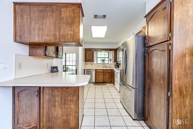3405 Shadyhill Dr, San Angelo, TX 76904 - kitchen featuring appliances with stainless steel finishes, a peninsula, light countertops, light tile patterned floors, and a sink