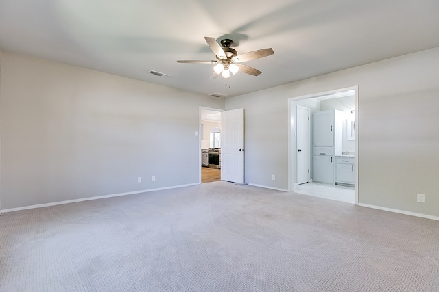 unfurnished bedroom with ceiling fan, connected bathroom, and light colored carpet