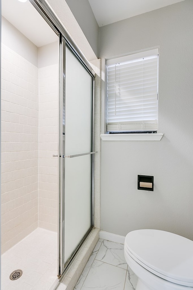 bathroom with a shower with door and toilet