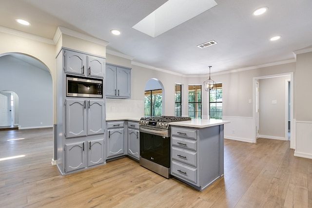 kitchen featuring light hardwood / wood-style floors, hanging light fixtures, stainless steel appliances, and kitchen peninsula