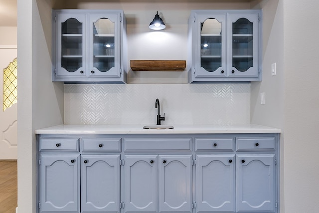 kitchen featuring gray cabinets, sink, and backsplash