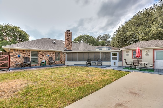 rear view of property featuring a yard, a patio area, and a sunroom