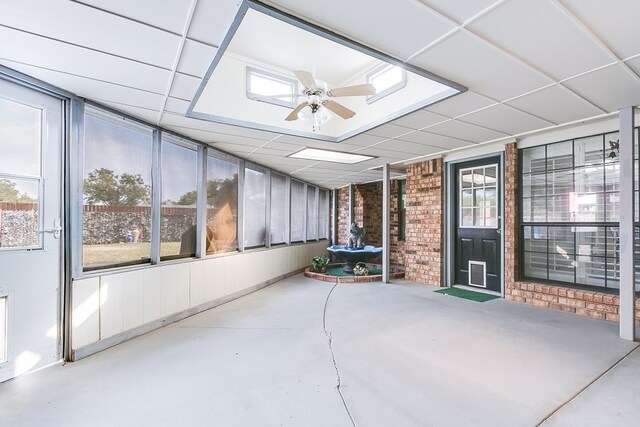 unfurnished sunroom with ceiling fan, a paneled ceiling, and a healthy amount of sunlight