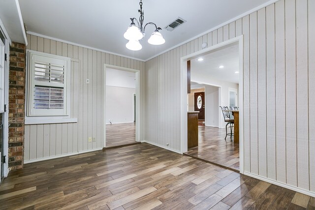 unfurnished dining area featuring hardwood / wood-style floors, a notable chandelier, and ornamental molding