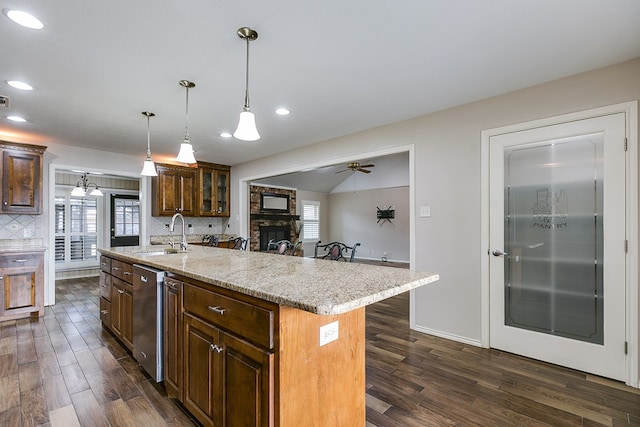 kitchen with dark wood-type flooring, a breakfast bar, sink, dishwasher, and a kitchen island with sink