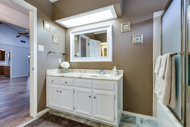 bathroom with shower / bath combination with glass door, a skylight, vanity, hardwood / wood-style flooring, and ceiling fan