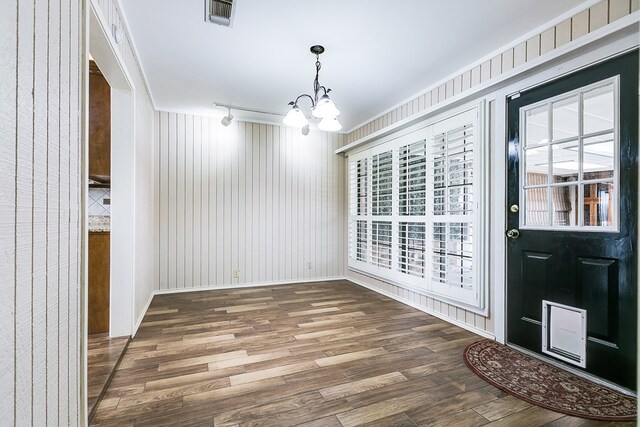 entrance foyer featuring wood-type flooring, plenty of natural light, crown molding, and a chandelier