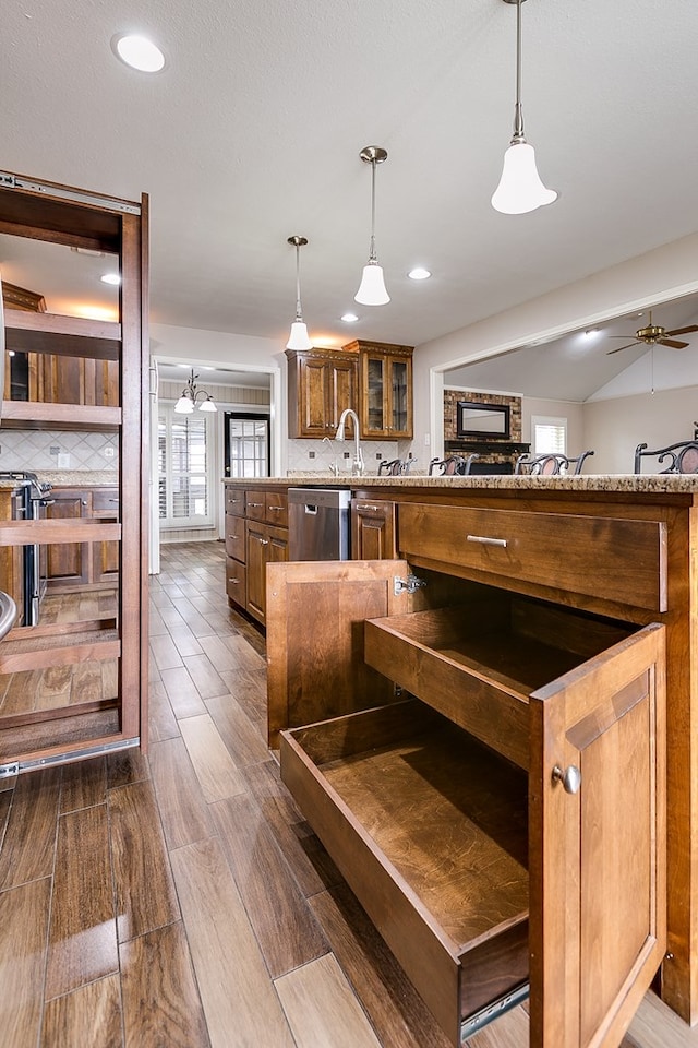 kitchen with decorative light fixtures, decorative backsplash, stainless steel dishwasher, ceiling fan, and dark wood-type flooring