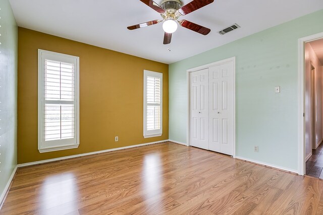 unfurnished bedroom featuring light hardwood / wood-style flooring, a closet, and ceiling fan