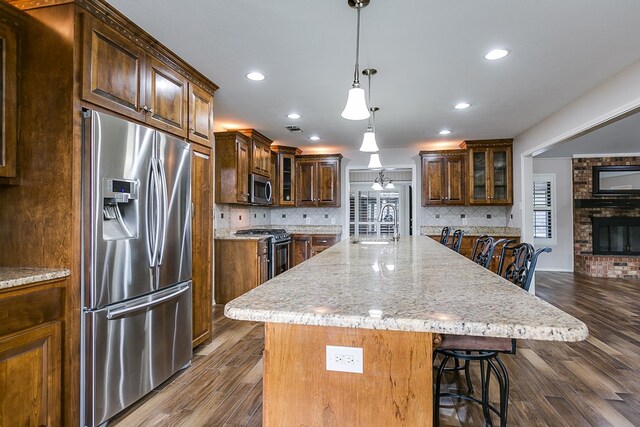 kitchen with an island with sink, sink, a kitchen breakfast bar, hanging light fixtures, and stainless steel appliances