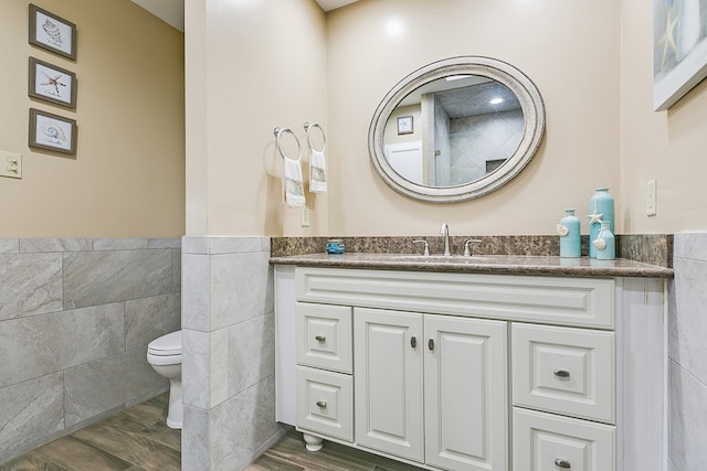 bathroom featuring vanity, toilet, hardwood / wood-style floors, and tile walls