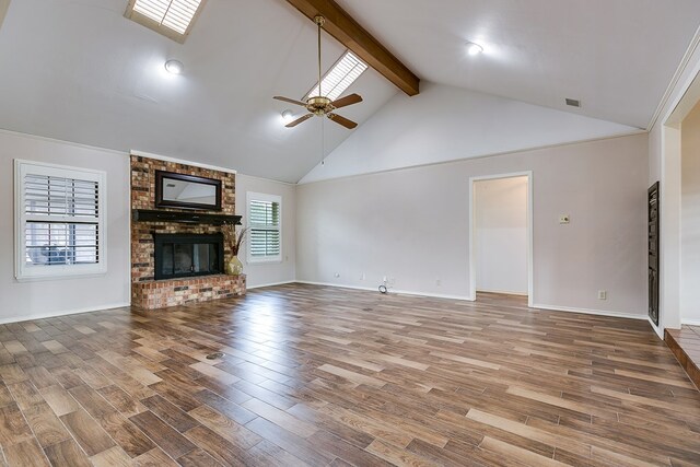 unfurnished living room featuring hardwood / wood-style flooring, ceiling fan, high vaulted ceiling, a brick fireplace, and beamed ceiling