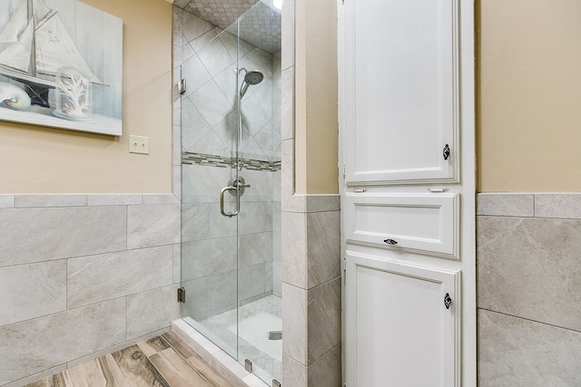 bathroom with tile walls and a shower with shower door