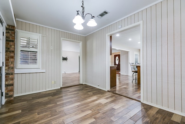 unfurnished dining area with ornamental molding, hardwood / wood-style floors, and an inviting chandelier