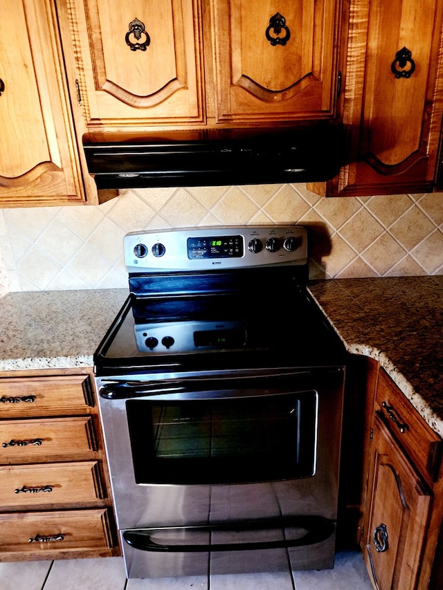 kitchen with light stone countertops, backsplash, and electric stove