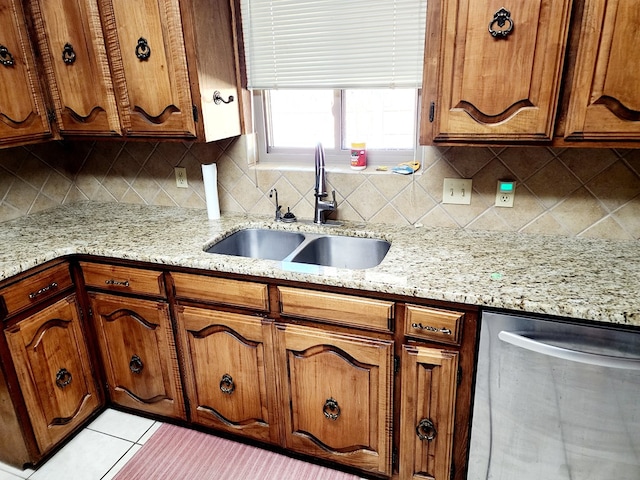 kitchen featuring light stone counters, dishwasher, sink, and decorative backsplash