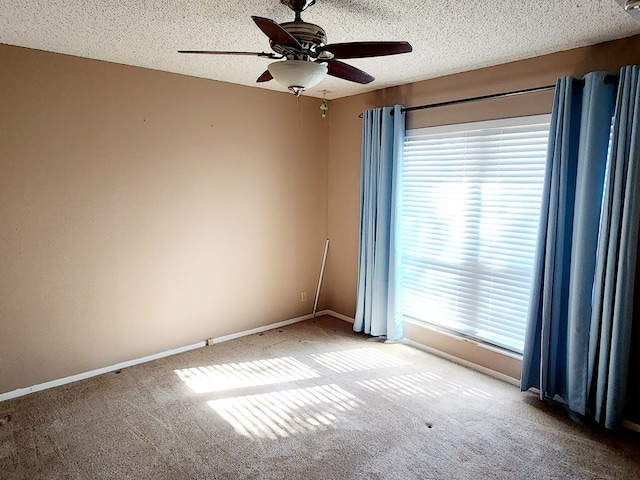 spare room featuring ceiling fan, light colored carpet, and a textured ceiling