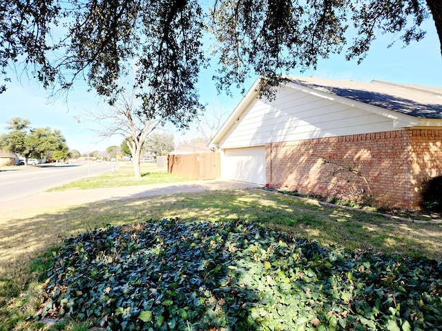 view of side of property featuring a garage and a lawn