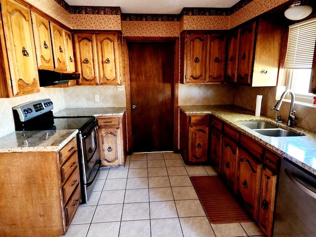 kitchen featuring sink, light tile patterned floors, stainless steel appliances, light stone counters, and a textured ceiling