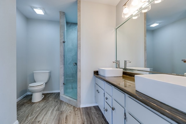 bathroom featuring hardwood / wood-style flooring, vanity, tiled shower, and toilet