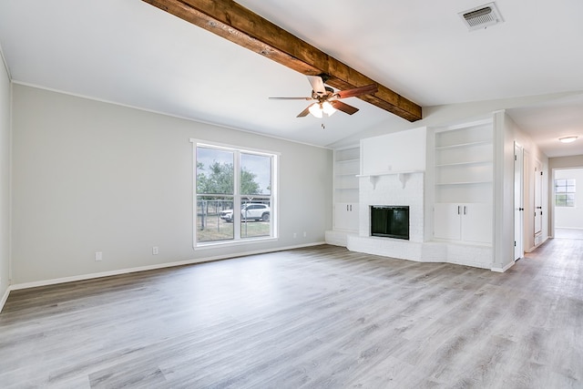 unfurnished living room with built in shelves, a fireplace, light wood-type flooring, and a wealth of natural light