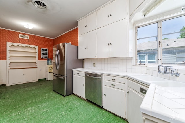 kitchen featuring sink, crown molding, appliances with stainless steel finishes, white cabinets, and tile countertops