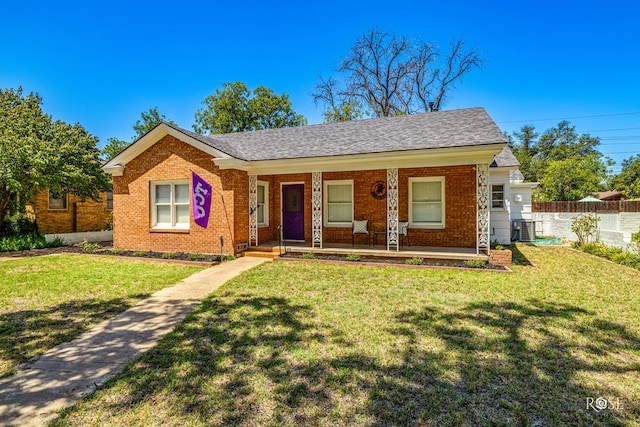 view of front of home with cooling unit, a front yard, and covered porch