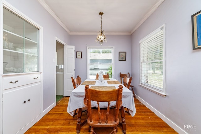 dining room with an inviting chandelier, crown molding, and wood-type flooring