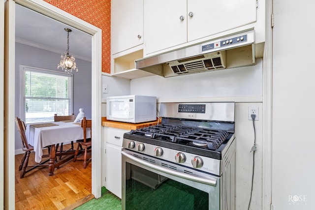 kitchen with white cabinetry, stainless steel range with gas cooktop, decorative light fixtures, and range hood