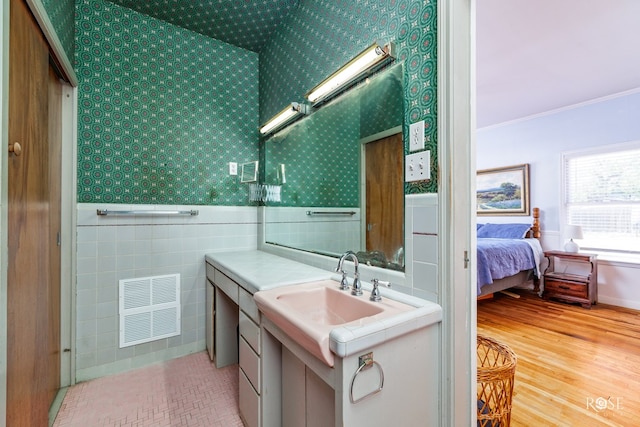 bathroom featuring crown molding, sink, hardwood / wood-style floors, and tile walls