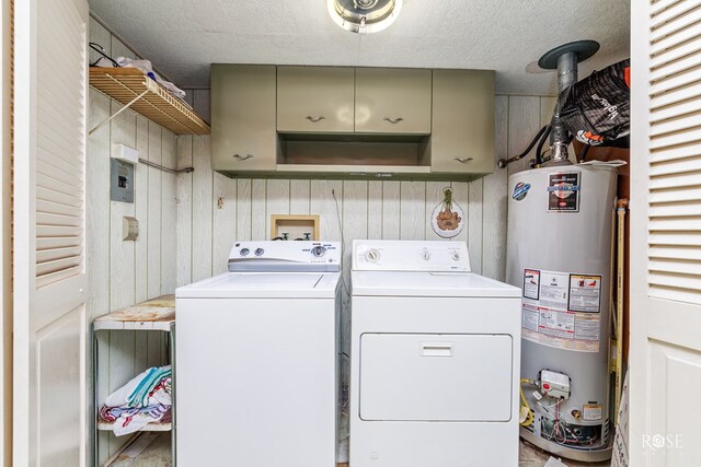 washroom with water heater, washer and dryer, and cabinets