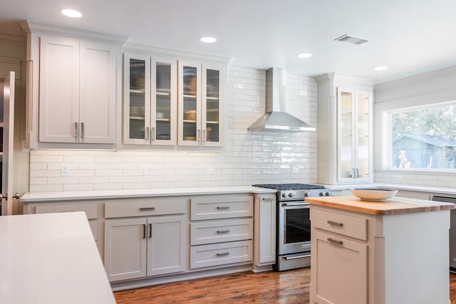 2611 Live Oak St, San Angelo, TX 76901 - kitchen featuring stainless steel range with gas cooktop, wall chimney range hood, butcher block counters, backsplash, and dishwashing machine