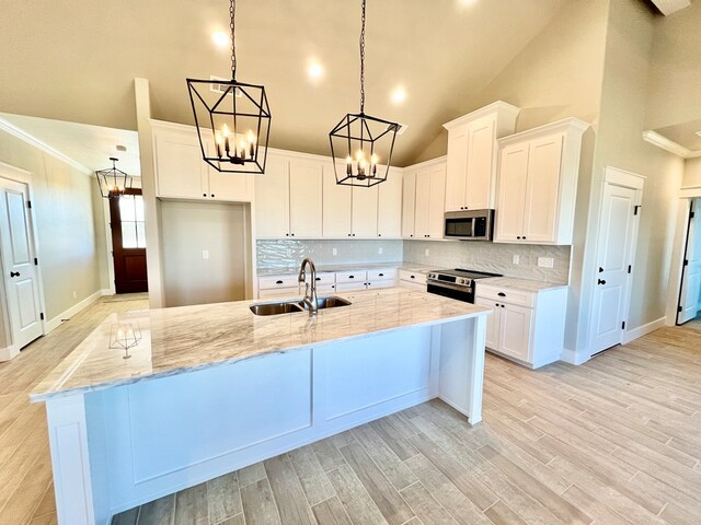 kitchen with white cabinetry, sink, stainless steel appliances, and a center island with sink