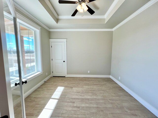 unfurnished room featuring ceiling fan, ornamental molding, and a tray ceiling