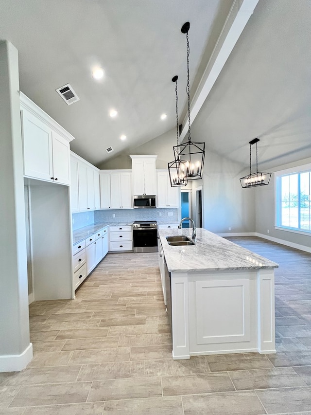 kitchen featuring pendant lighting, white cabinetry, sink, stainless steel appliances, and a center island with sink