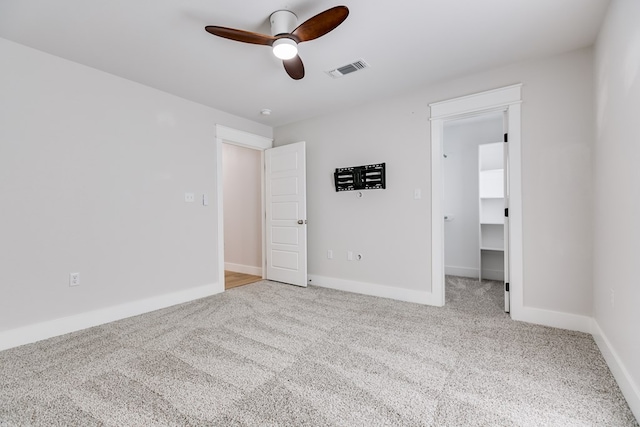 unfurnished bedroom with carpet flooring, baseboards, visible vents, and a walk in closet