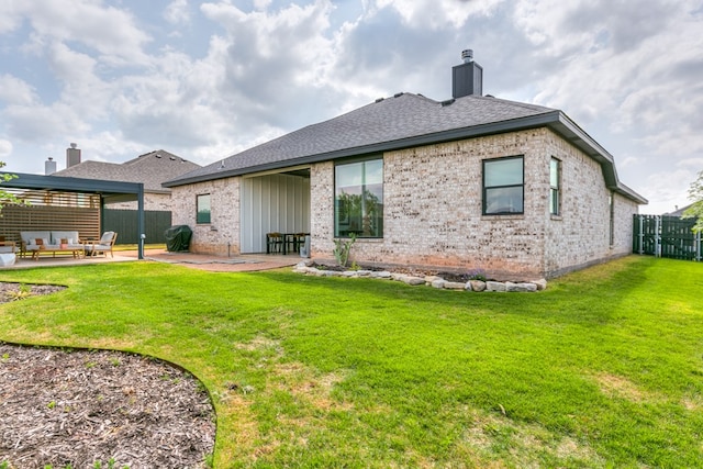 rear view of property featuring a chimney, a lawn, a patio area, brick siding, and a fenced backyard